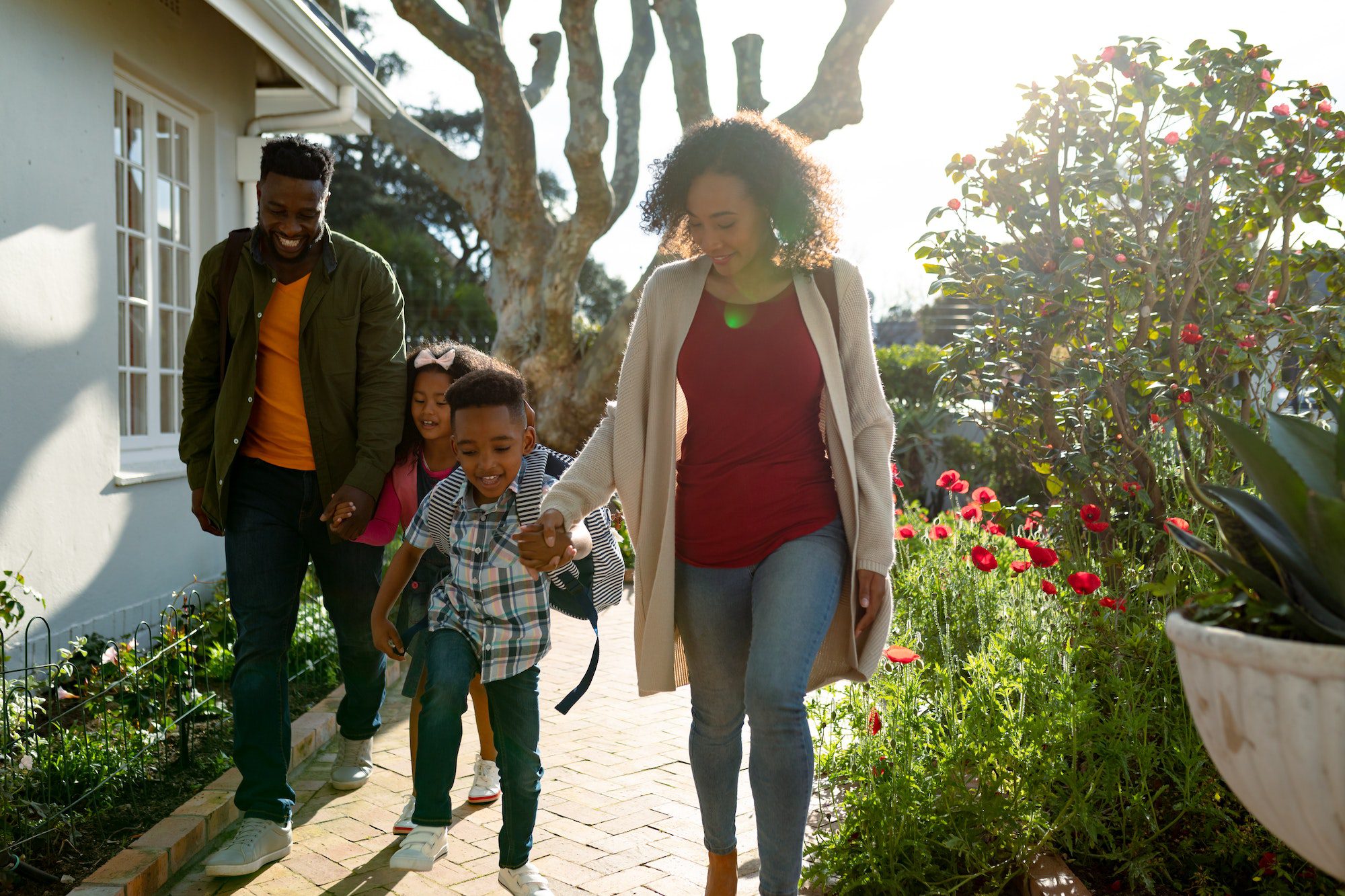 Happy african american family holding hands and walking outside