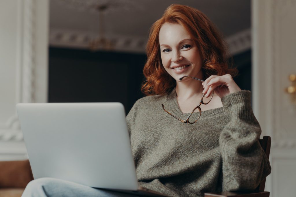 Professional positive redhead young European woman works on freelance