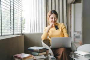 Asian woman holding a credit card and using a laptop computer Businesswoman working at modern office