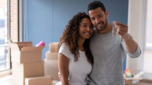 Portrait of a loving couple buying a house and holding the keys while smiling - real estate concepts