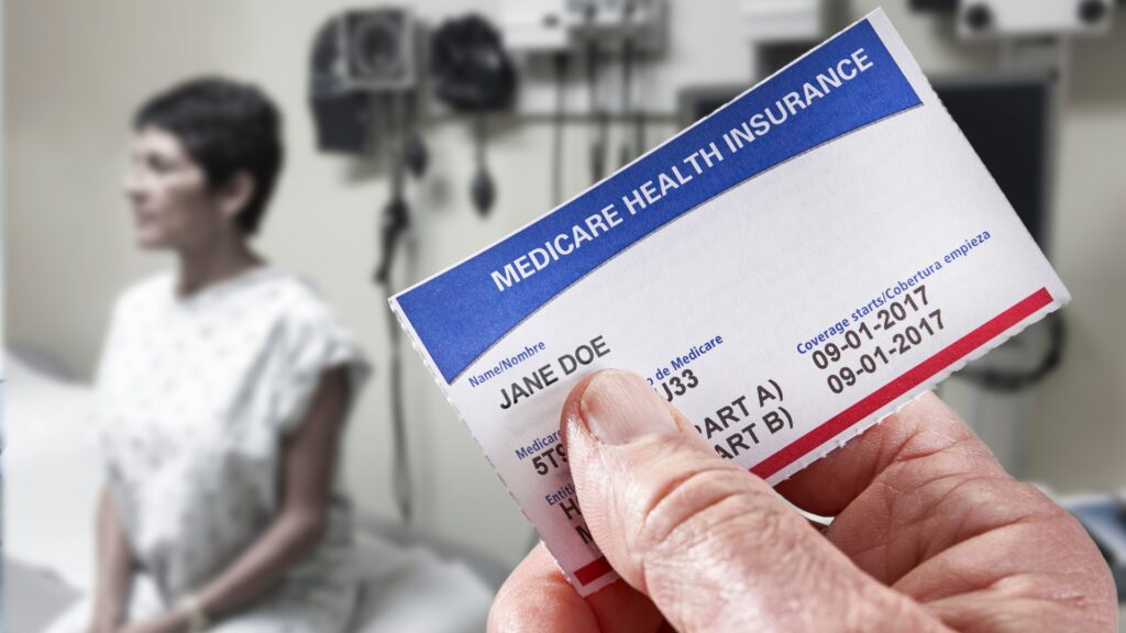 Medicare health insurance card in hospital setting with patient in the background.